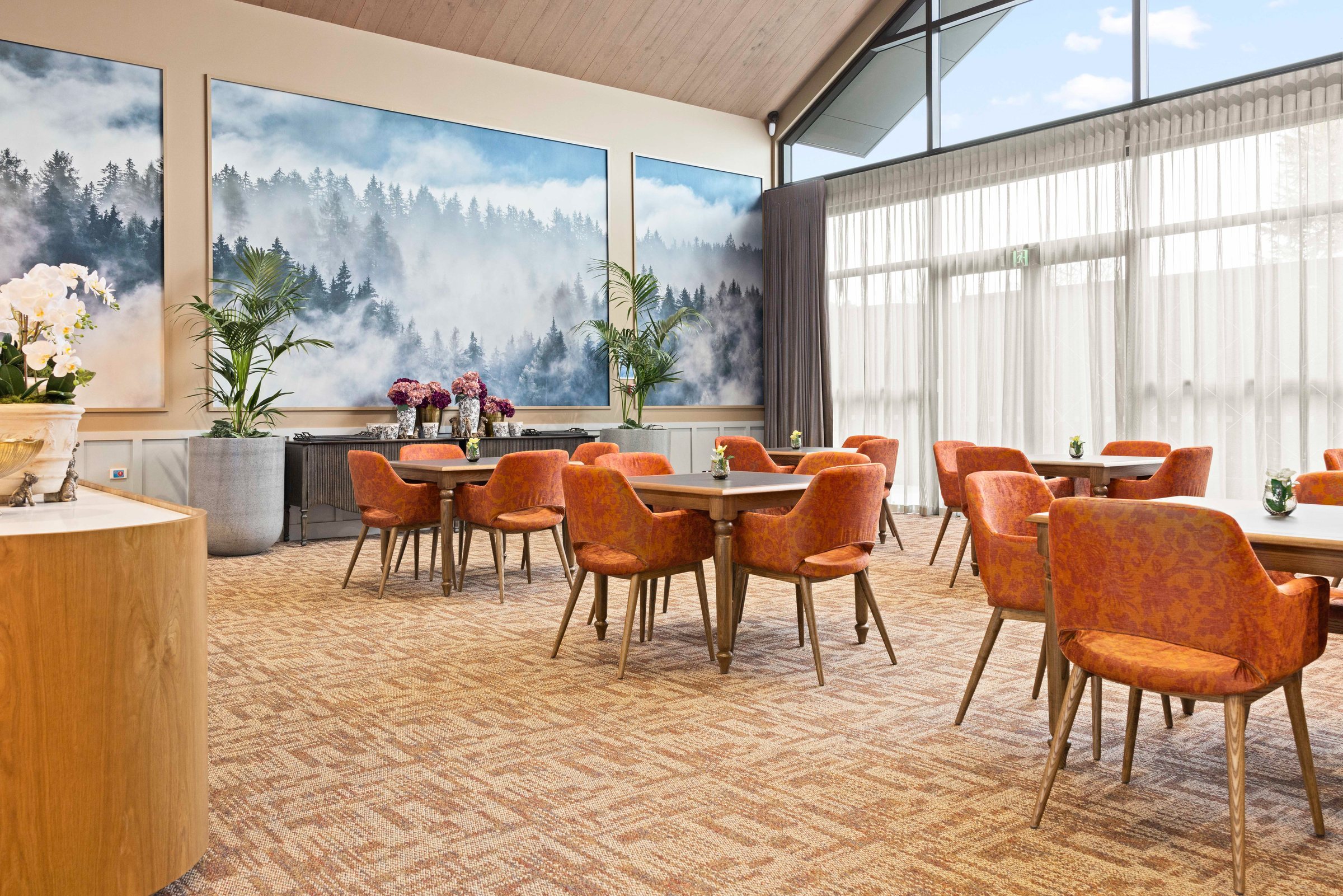Dining room at Tamahere Country Club with orange armchairs and a misty forest mural, photographed for Acorn Furniture