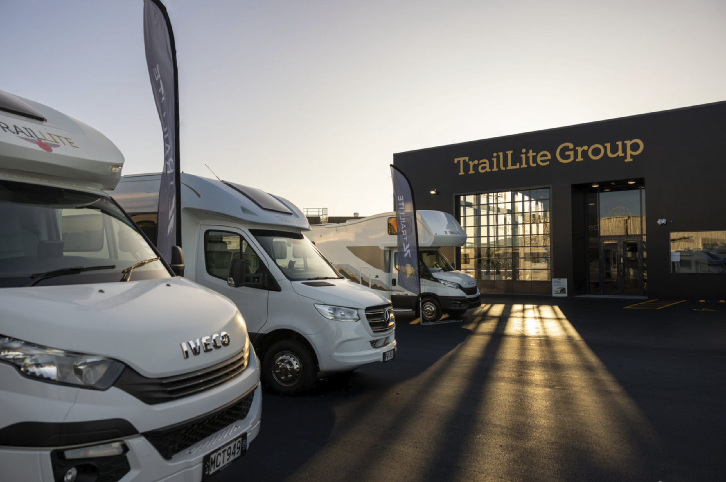 Recreational vehicles parked outside the TrailLite Group building at sunset