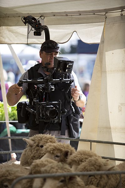 Operator filming sheep with a stabilised gimbal rig at an agricultural show