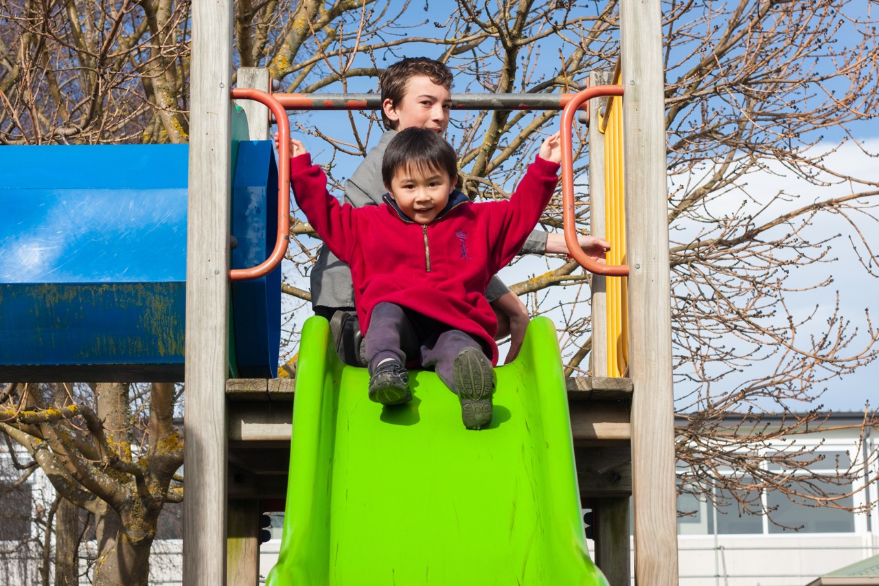 Two Christ the King School students on a slide in the playground