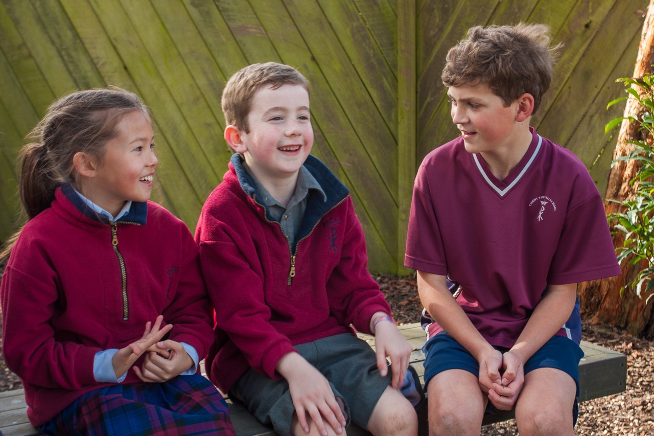 Three Christ the King School students sitting together talking in the garden